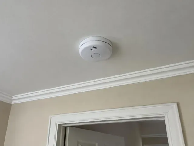 Ceiling smoke alarm above a doorway in a beige home interior in Fairlight